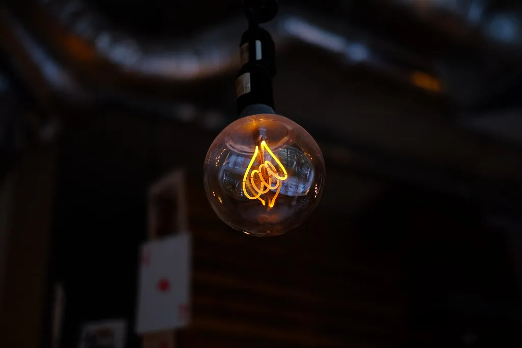 A glowing decorative light bulb hanging against a dark background