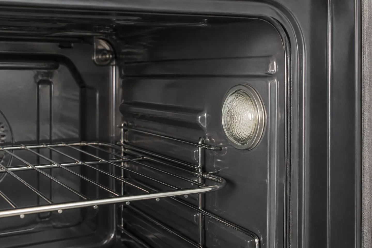 Switched-off oven cavity with a protected light cover on the side wall